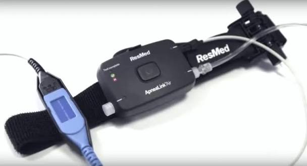 Dispositivo montado sobre el cinturón negro, con el sensor de esfuerzo a la derecha y el oxímetro con su sensor de dedo a la izquierda
