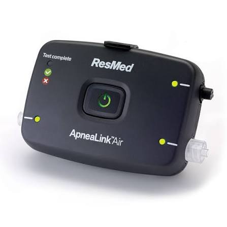 Vista frontal del dispositivo ApneaLink Air: arriba a la izquierda los indicadores de Test complete con una palomita verde y un tache rojo, el botón de encendido circular en el centro y tres luces de accesorio en los bordes