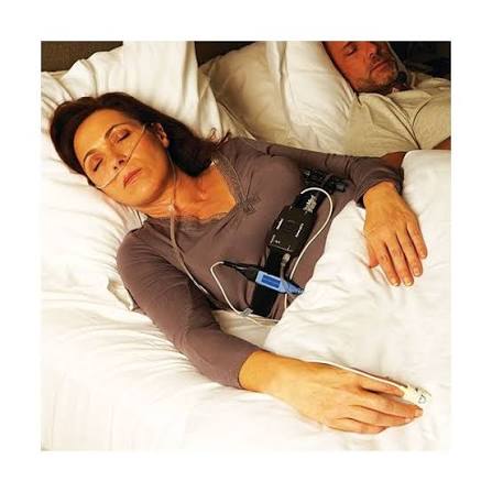 Mujer durmiendo de lado con la cánula nasal, el dispositivo en el pecho y el sensor en el dedo de la mano